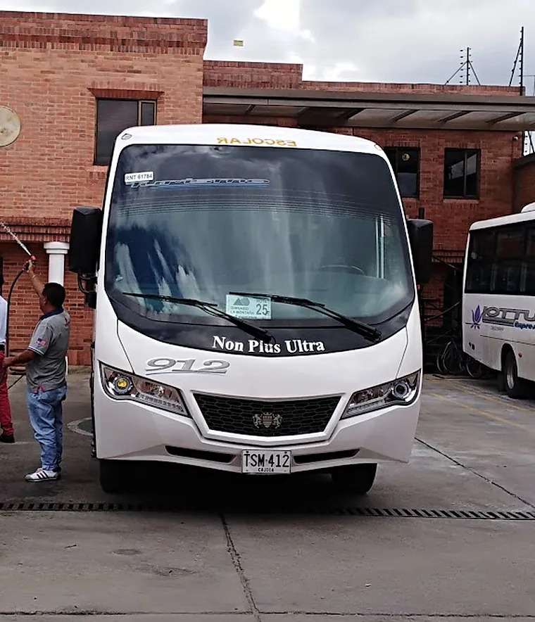Microbús escolar de Lottus Express en el patio, con la palabra ESCOLAR en el parabrisas